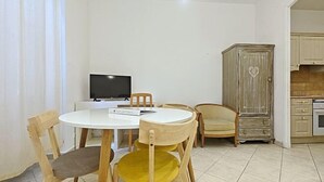 A dining area with a round table, wooden chairs, a television, and a cabinet. - Viva Riviera 11 Rue Commandant Andre (Cannes)
