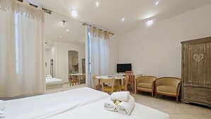 A hotel room with two beds, a desk, two chairs, a TV, and a wardrobe. - Viva Riviera 11 Rue Commandant Andre (Cannes)