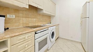 A kitchen with a washing machine, a stove, and cabinets. - Viva Riviera 11 Rue Commandant Andre (Cannes)