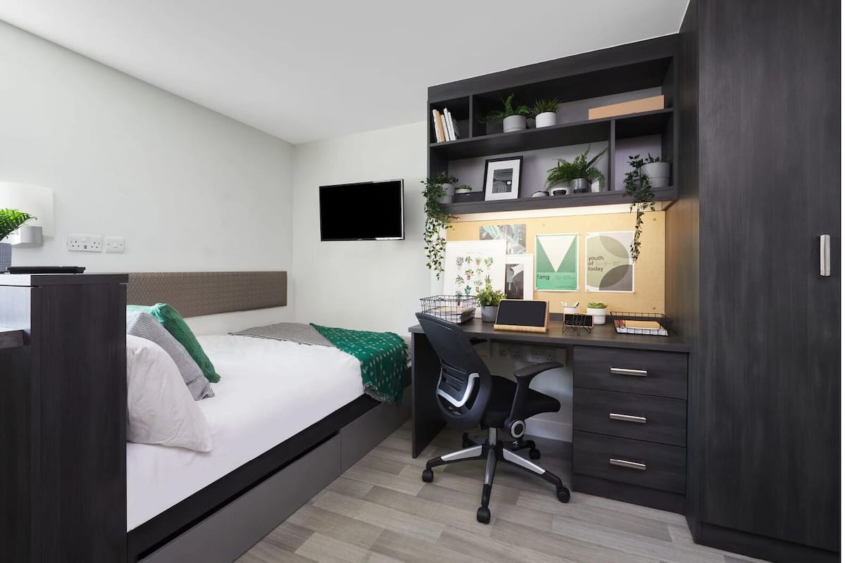 Ein modernes Schlafzimmer mit Bett, Schreibtisch, Stuhl und Kleiderschrank.
