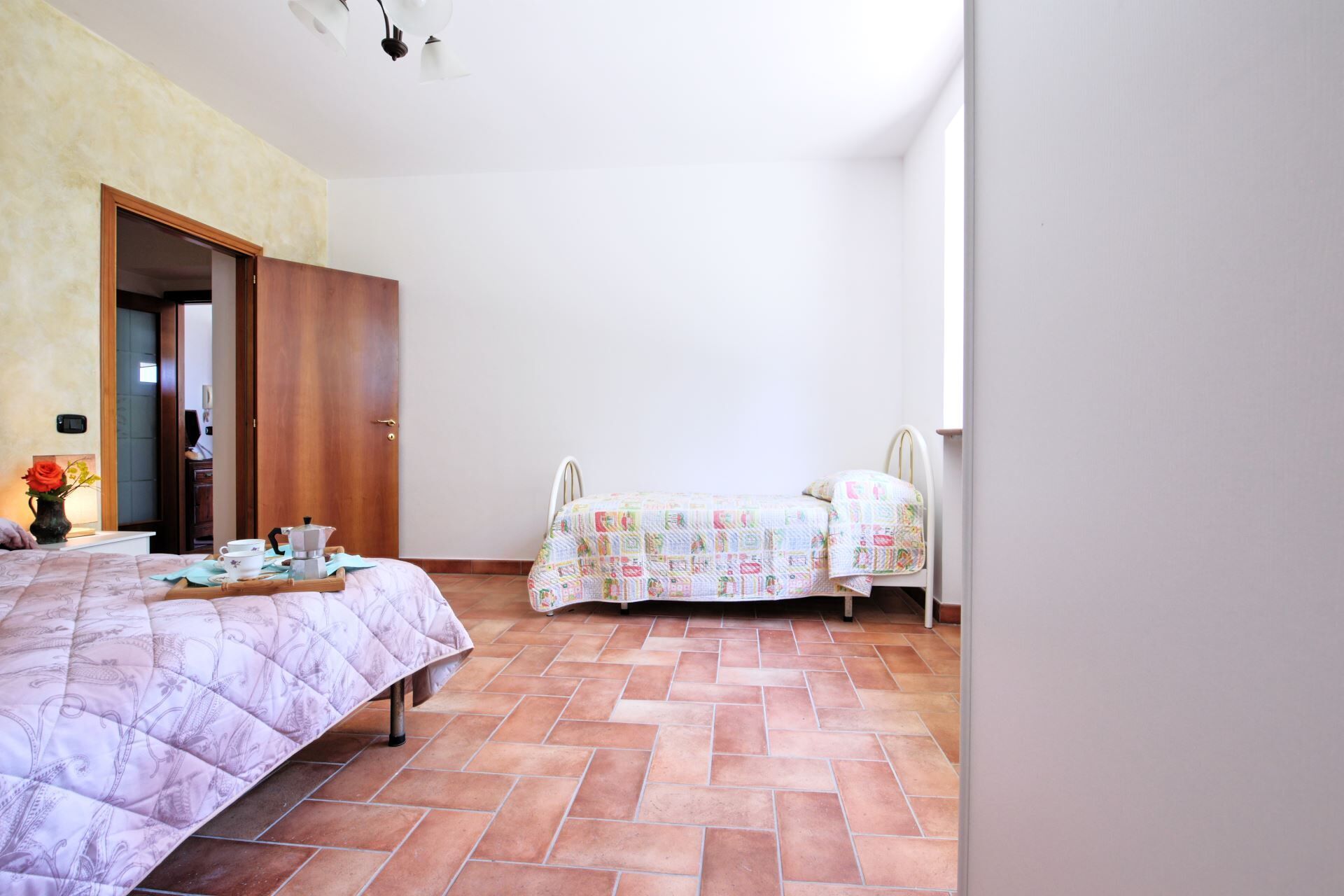 Een slaapkamer met een bed, nachtkastje, kledingkast en raam.