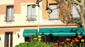 A hotel with a green awning, a sign reading 'HOTEL DE PROVENCE,' and a garden with tulips. - Hotel Provence by Adonis (Digne-les-Bains)
