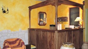 A wooden reception desk with a mirror above it, a lamp, and a vase on the floor. - Hotel Provence by Adonis (Digne-les-Bains)