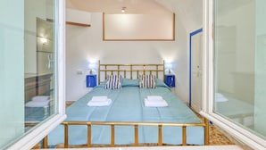 Un dormitorio con una cama, dos mesitas de noche, una ventana y un espejo.