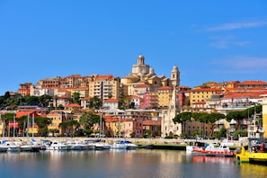 Experience the charm of a picturesque coastal town with a vibrant harbor, colorful buildings, and a historic church with a dome and bell tower.