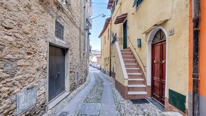 Una estrecha calle empedrada flanqueada por edificios históricos de muros de piedra y puertas de madera.