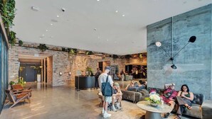 A spacious lobby with a brick wall, a reception desk, seating areas, and a modern light fixture. - Luxury Miami Studio Bay Views | 37th Fl (Miami)