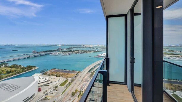 A high-rise building with a balcony overlooking a coastal cityscape, including a bridge and marina. - Luxury Miami Studio Bay Views | 37th Fl (Miami)
