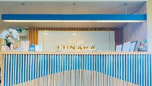 Een receptiebalie met een blauw-wit kleurenschema, met een bord waarop 'The Grand LUNARA' staat.