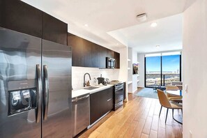 A modern kitchen with stainless steel appliances, a large window, and a view of the city.