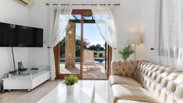 Relax in this stylish living room with a flat-screen TV, comfortable sofa, and a beautiful view of the outdoor area.