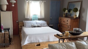 Un dormitorio con cama, cómoda de madera y sofá.