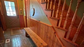 Interior de madera con un banco, una escalera y una puerta.