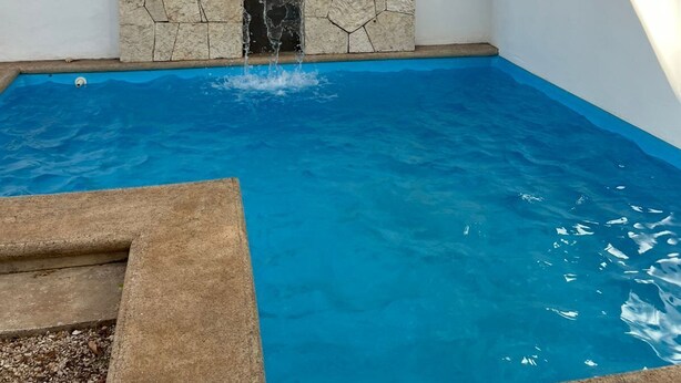 A swimming pool with a stone waterfall feature and a clear blue pool.