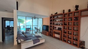 A modern living room with a sofa, TV, and wooden shelving unit.