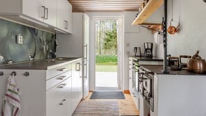 A modern kitchen with white cabinets, stainless steel appliances, and a wooden ceiling. - Klägghult by Interhome (Kalv)