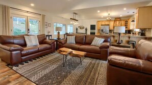 A spacious living room with leather sofas, a patterned rug, and a wooden coffee table. - Yosemite Quail Ridge Comforts with WiFi and Hot tub (Mariposa)