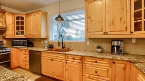 A kitchen with wooden cabinets, a granite countertop, a sink, a microwave, and a coffee maker. - Yosemite Quail Ridge Comforts with WiFi and Hot tub (Mariposa)