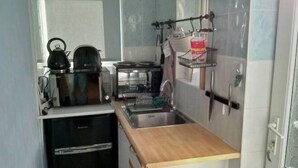 A compact kitchen with a black refrigerator, a stove, a sink, and a wooden countertop. - Peaceful House in the Centre of City (Lancaster)