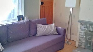 A room with a purple sofa, a white lamp, and a fireplace. - Peaceful House in the Centre of City (Lancaster)