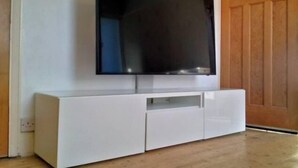 A white entertainment unit with a flat-screen TV mounted above it. - Peaceful House in the Centre of City (Lancaster)