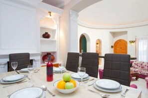 Comedor con una mesa dispuesta para seis personas, con platos, vasos y un frutero.