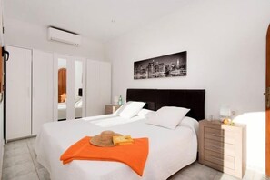 Ein Hotelzimmer mit Bett, Nachttisch, Kleiderschrank und einem Stadtbild an der Wand.