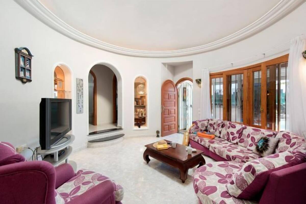 A living room with a sofa, a coffee table, a television, and a fireplace.