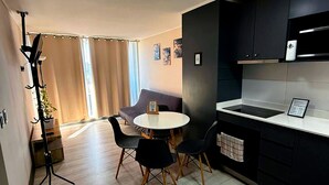 Una cocina compacta con zona de comedor, una lámpara de pie y una planta en maceta.