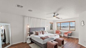 A bedroom with a bed, bedside tables, a ceiling fan, a window, and a chair.