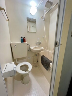 Un baño pequeño con inodoro, lavamanos y ducha.