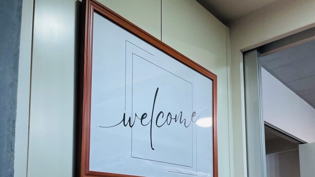 A framed welcome sign with the word "welcome" in cursive on a light background, mounted on a wall above a white shelf. - 15min Shinjuku/5min Hatsudai(OperaCityDirect).Quiet,perfect place/Early check-in (Shinjuku City)