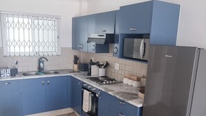 A modern kitchen with blue cabinets, stainless steel appliances, and a tiled floor.