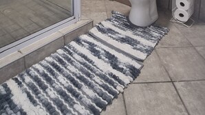A bathroom with a shower, toilet, and a rug.
