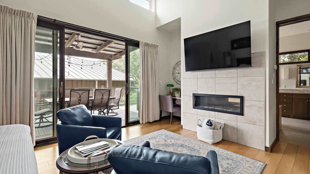Una sala moderna con chimenea, televisor y comedor con mobiliario exterior.