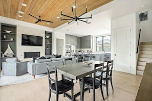 A modern kitchen with a dining area, built-in shelves, and a large window.