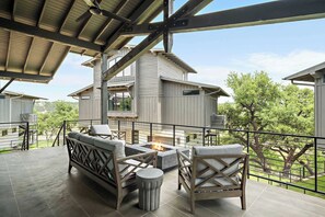 A covered outdoor seating area with a fire pit, a sofa, and two chairs.