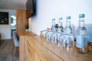 A wooden bar counter with several clear glass bottles and a few empty glasses. - Suite 8 - Sleeping Giant Hotel - PEN Y CAE Inn (Swansea)