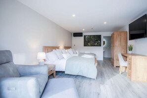 Une chambre moderne avec un grand lit, un bureau et un téléviseur.