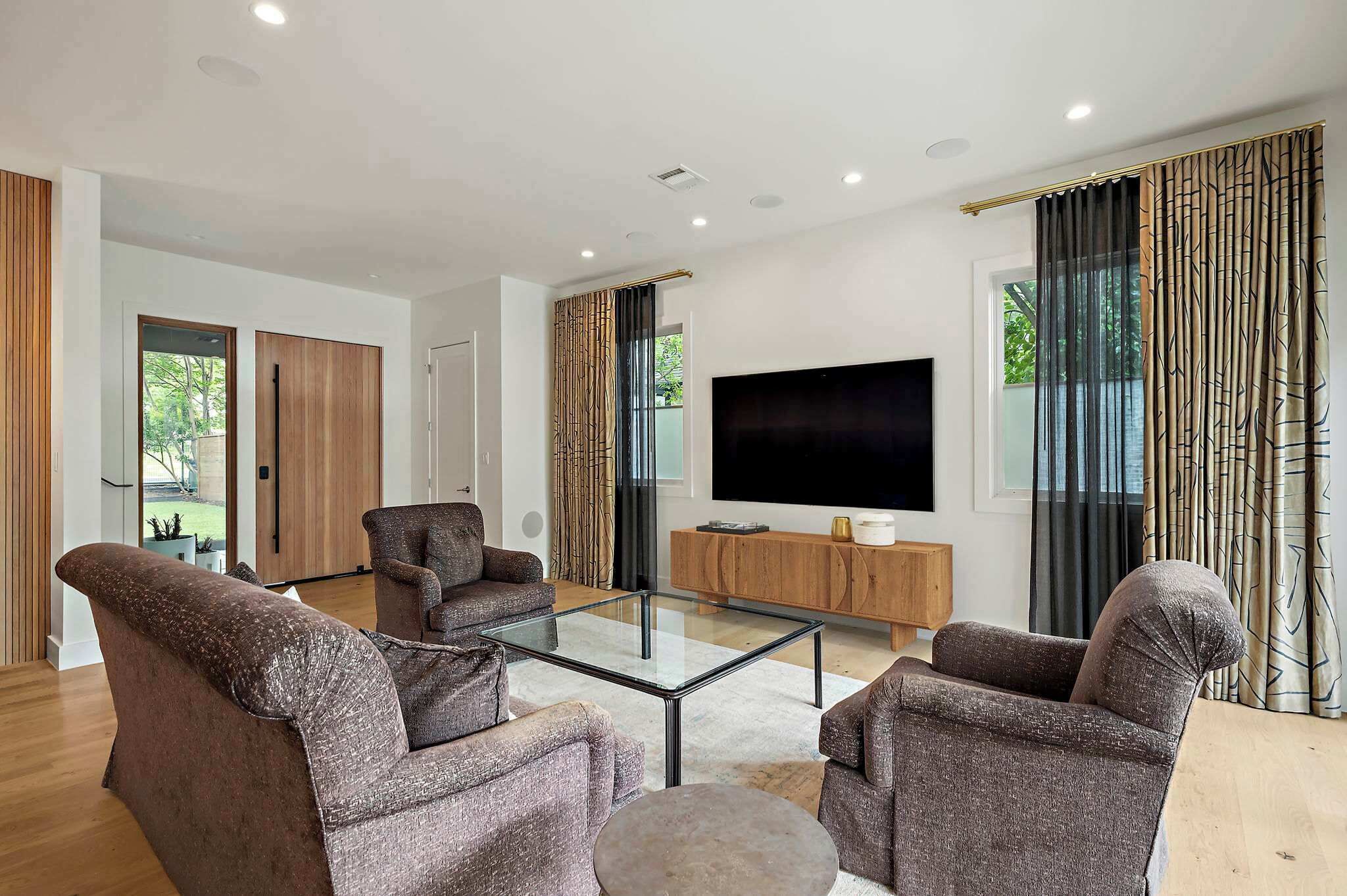 Een moderne woonkamer met een glazen salontafel, twee banken, een televisie en een houten kast.