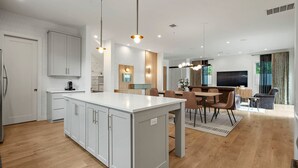 Una cocina moderna con armarios blancos, una isla central e iluminación colgante.