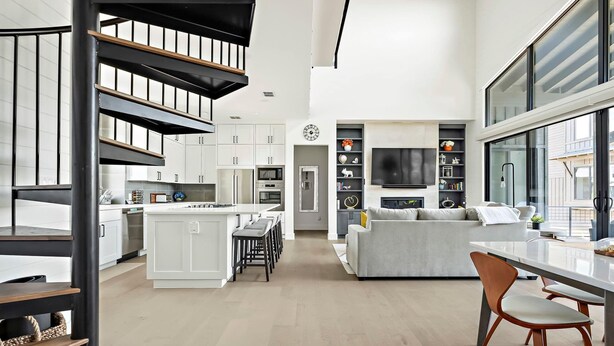 A modern kitchen with white cabinets, a central island, and a dining area with a table and chairs. - Lake Travis Getaway / Pickleball / Grill / Firepit (Lake Travis)