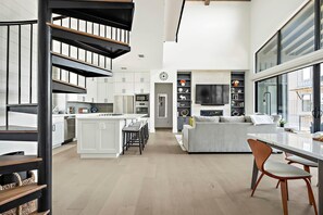 Een moderne keuken met witte kasten, een centraal eiland en een eethoek met een tafel en stoelen.