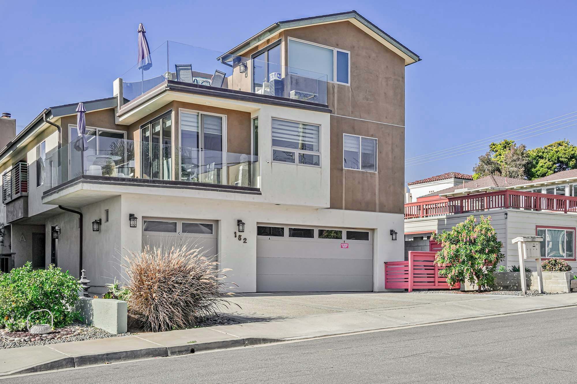 Une maison moderne à deux étages, dotée d’un garage, d’un balcon et offrant une vue dégagée sur la rue.
