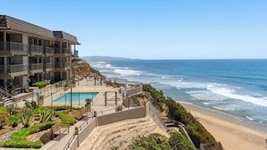 Un hôtel situé en bord de mer, doté d’une piscine, de plusieurs balcons et offrant une vue sur l’océan.