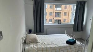 Un dormitorio con una cama, una mesa redonda y un ventanal con cortinas.