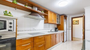 Una cocina con armarios de madera, horno empotrado, microondas y refrigerador.