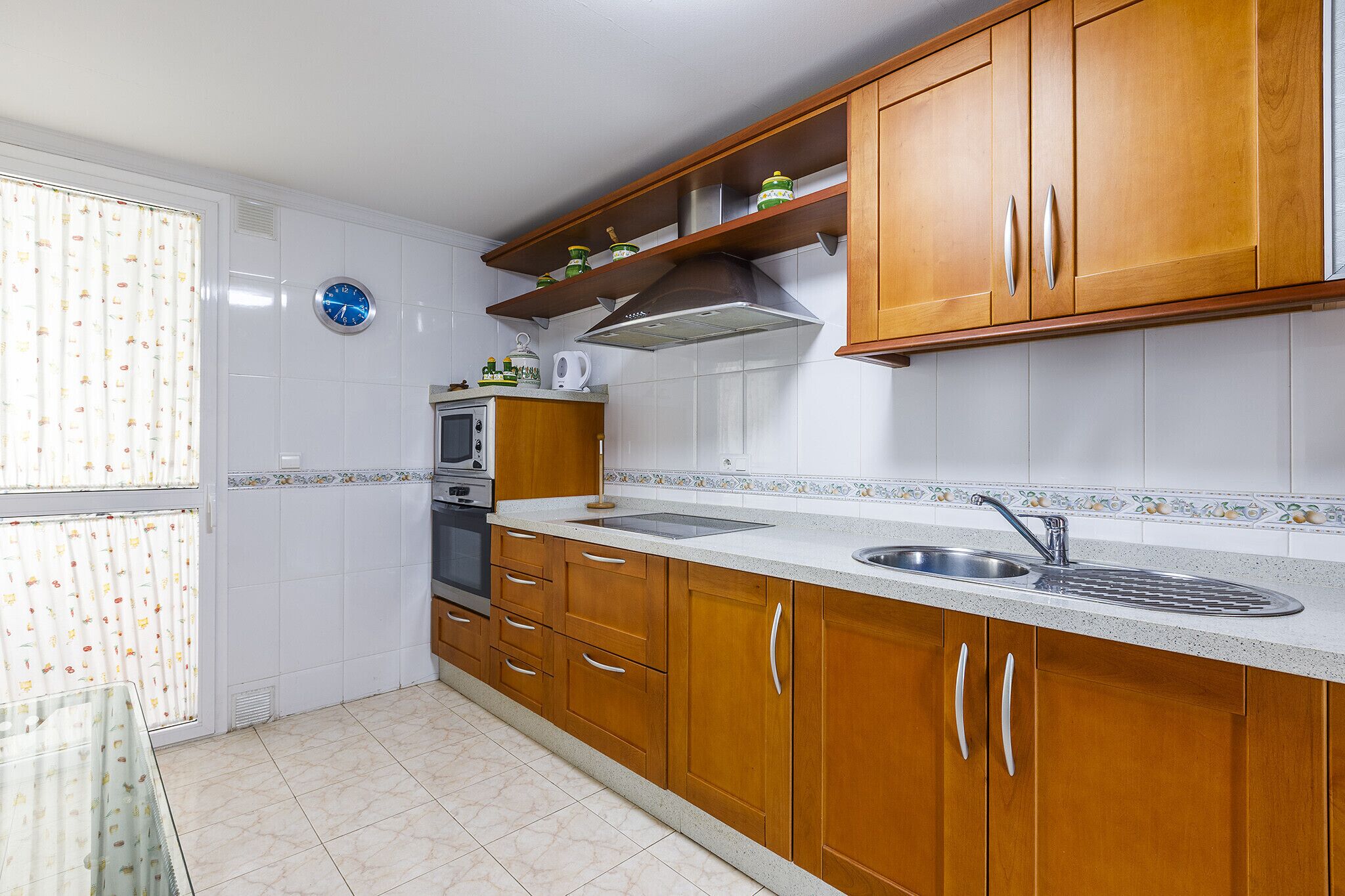 A kitchen with wooden cabinets, a stainless steel sink, and a microwave.
