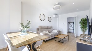 A modern living room with a wooden dining table, white chairs, a grey sofa, and a small coffee table. - A&N Seafront 2 (Torre del Mar)