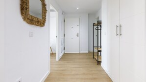 A hallway with a mirror, a door, and a rack with clothes. - A&N Seafront 2 (Torre del Mar)